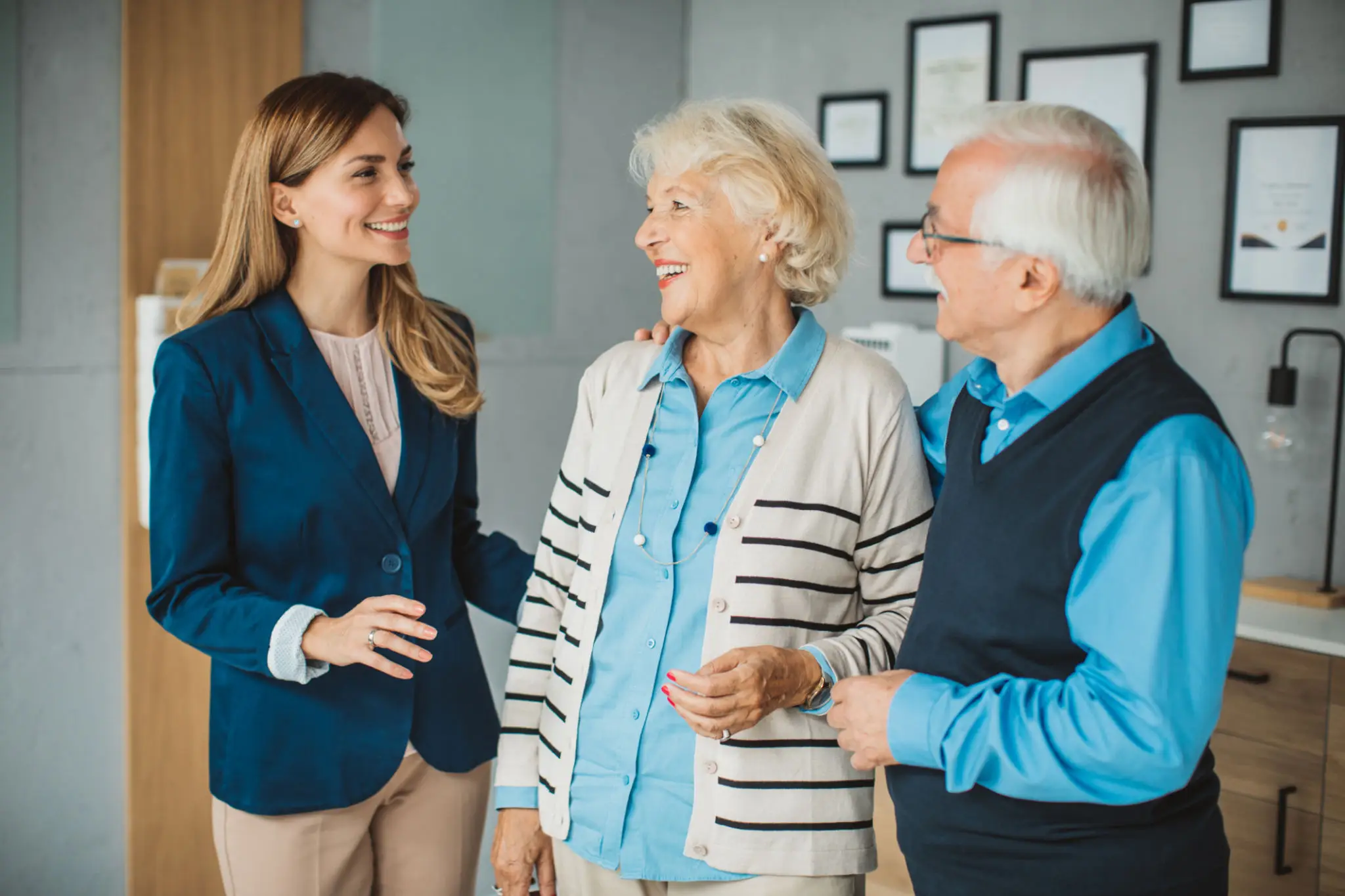 A young professional woman talking with an elderly couple in a friendly setting.